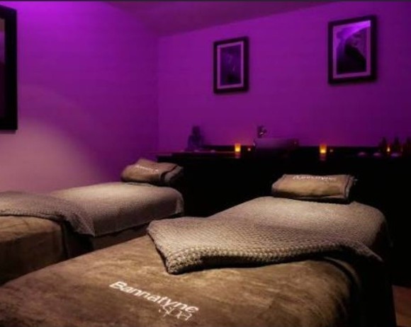 Dual treatment room at Bannatyne Spa Luton, with two treatment beds under low purple lighting and candles